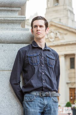 Gözlerini kısarak, genç ve yakışıklı bir adam dışarıda düşünüyor.