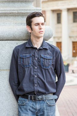 Gözlerini kısarak, genç ve yakışıklı bir adam dışarıda düşünüyor.