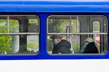 Riga, Letonya - 14 Mayıs 2020: tramvay yolcuları tıbbi maskeli, yarı çıplak bir toplu taşıma aracının penceresinden Coronavirus Önleme