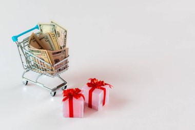 Noel masraf planlama konsepti, hediye kutuları ve para dolu alışveriş arabası, beyazlar içinde izole edilmiş.