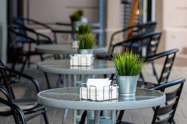 Boş masaları ve sandalyeleri olan kaldırım restoranı.