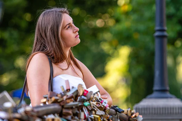 Young Woman Stands Bridge Love Locks Stares Dreamily Distance Defocused — Stock Photo, Image