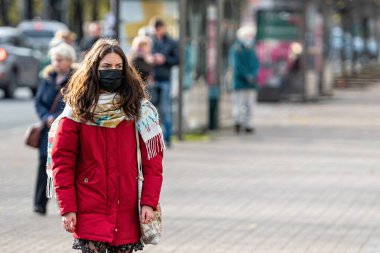 Riga, Letonya - 6 Kasım 2020: Coronavirus pandemik kısıtlamaları sırasında tıbbi yüz maskeleri takan insanlar, covid-19 virüsünün yayılması ile mücadele eden bir konsept.