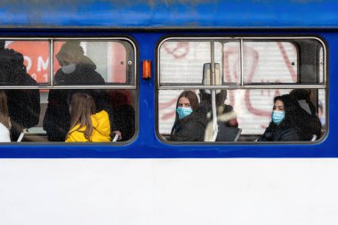Riga, Letonya - 6 Kasım 2020: Toplu taşımacılık, koronavirüs koruma konsepti pencerelerinde yüzlerinde tıbbi maske olan insanlar
