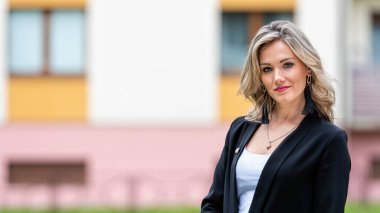 Bulanık şehir arka planına karşı genç, pozitif, zarif bir iş kadınının portresi.