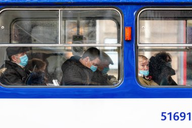 Riga, Letonya - 6 Kasım 2020: Toplu taşımacılık, koronavirüs koruma konsepti pencerelerinde yüzlerinde tıbbi maske olan insanlar
