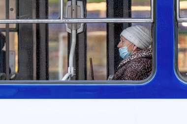 Riga, Letonya - 6 Kasım 2020: Toplu taşımacılık, koronavirüs koruma konsepti pencerelerinde yüzlerinde tıbbi maske olan insanlar