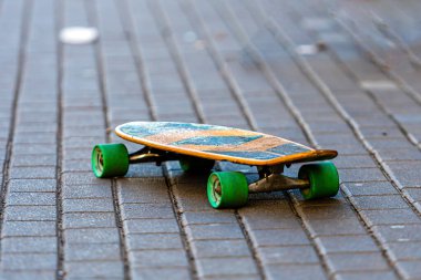 Asfaltlı kaldırımda yeşil tekerlekleri olan kaykay, yakın plan.