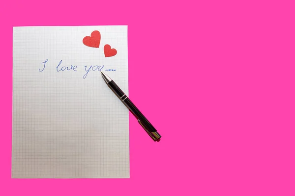 love letter, pen and envelote vith little paper hearts on pink background, close-up
