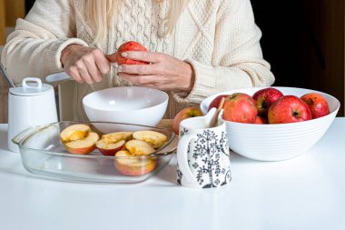 Kadın eli bir elmayı kesti ve pişirmek için hazırladı, beyaz bir kasede, elmalı, bayram için ev yapımı pişirme konsepti.