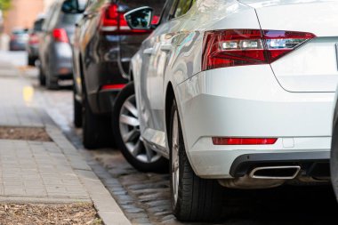 Kalabalık şehirde yol kenarına park edilmiş sıra sıra farklı arabalar.