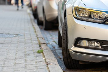 Kalabalık şehirde yol kenarına park edilmiş sıra sıra farklı arabalar.