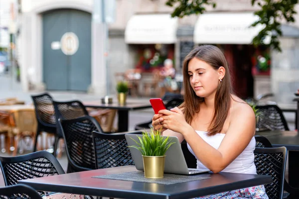 Mujer Joven Trabaja Ordenador Portátil Uso Teléfono Sentado Cafetería Calle —  Fotos de Stock