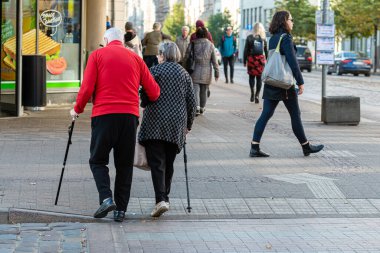 Riga, Letonya - 7 Ekim 2020: bastonlu iki yaşlı insan caddenin karşısına geçer.