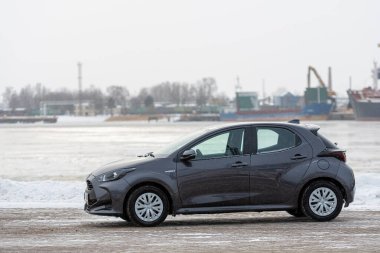 Riga, Letonya - 9 Şubat 2021: Metalik gri Toyota Yaris Hybrid Y20 versiyonu Hatchback arabası deniz kenarına park edilmiş.