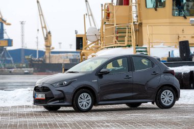Riga, Letonya - 9 Şubat 2021: Metalik gri Toyota Yaris Hybrid Y20 model araba endüstriyel arka planda