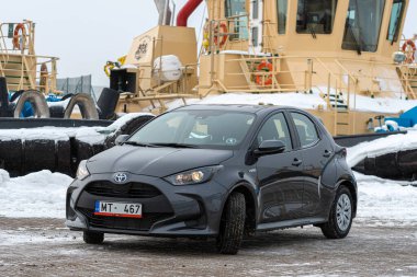 Riga, Letonya - 9 Şubat 2021: Metalik gri Toyota Yaris Hybrid Y20 model araba endüstriyel arka planda