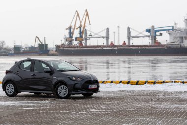 Riga, Letonya - 9 Şubat 2021: Metalik gri Toyota Yaris Hybrid Y20 versiyonu Hatchback arabası deniz kenarına park edilmiş.