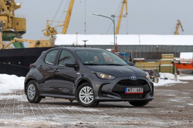 Riga, Letonya - 9 Şubat 2021: Metalik gri Toyota Yaris Hybrid Y20 model araba endüstriyel arka planda
