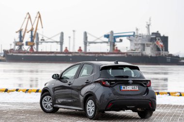 Riga, Letonya - 9 Şubat 2021: Metalik gri Toyota Yaris Hybrid Y20 versiyonu Hatchback arabası deniz kenarına park edilmiş.