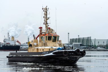 Riga, Letonya - 9 Şubat 2021: Römorkör, soğuk ve sisli bir kış sabahı kargo limanına döner.