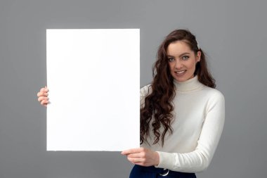 Uzun kıvırcık saçlı, güzel, şehvetli bir iş kadını boş bir reklam panosu gösteriyor.