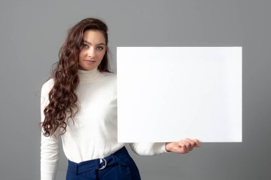 Uzun kıvırcık saçlı, güzel, şehvetli bir iş kadını boş bir reklam panosu gösteriyor.