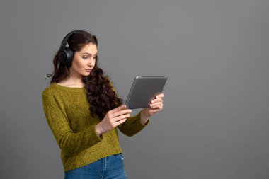 Elinde tablet ve kulaklığı olan bir kadın oyun oynuyor ve arkadaşlarıyla internet üzerinden konuşuyor, modern eğlence konsepti.