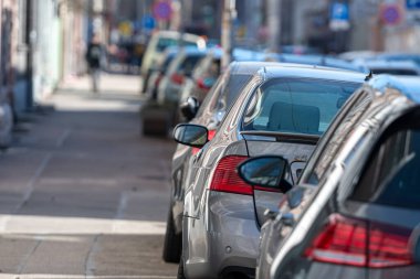 Kalabalık şehirde yol kenarına park edilmiş sıra sıra farklı arabalar, yakın çekim, seçici odak