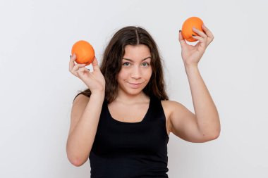 Beyaz arka planda izole edilmiş, ellerinde portakal meyveleri olan çekici genç bir kız.
