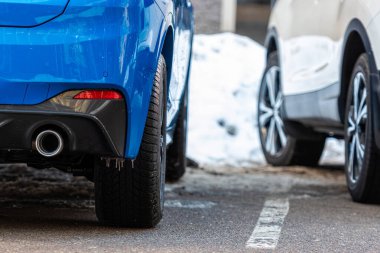 Caddenin kenarına park edilmiş mavi beyaz bir arabanın yakın çekimi.