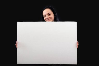 Koyu renk saçlı, gri kazaklı, beyaz posterli, koyu tenli, çekici bir kadın.