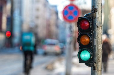 Şehir trafiğinin arka planına yeşil ışık yakılmış küçük bir trafik semaforu.