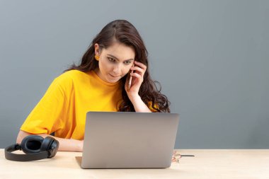 Genç bayan masada oturuyor, çalışırken modern teknolojiyi kullanıyor, online çalışma konsepti