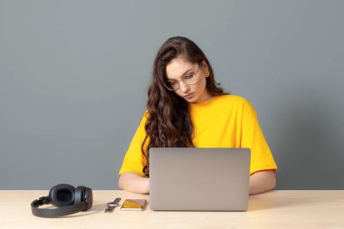 Genç bayan masada oturuyor, çalışırken modern teknolojiyi kullanıyor, online çalışma konsepti