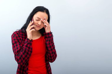 Koyu renk saçlı, kırmızı elbiseli genç bir kadın cep telefonuyla konuşuyor, aydınlık arka planda izole edilmiş.