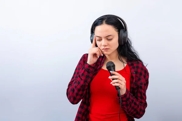 expressive female singing with a microphone and headphones, isolated on light background, mock up, copy space