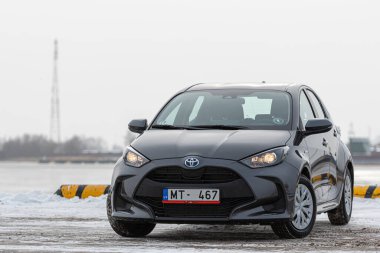 Riga, Letonya - 9 Şubat 2021: Metalik gri Toyota Yaris Hybrid Y20 versiyonu Hatchback arabası deniz kenarına park edilmiş.
