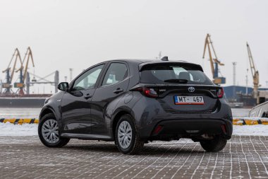 Riga, Letonya - 9 Şubat 2021: Metalik gri Toyota Yaris Hybrid Y20 versiyonu Hatchback arabası deniz kenarına park edilmiş.