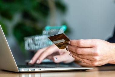 Kredi kartı, dizüstü bilgisayar ve e-ticaret konseptiyle internetten alışveriş yapan bir kadının yakın plan fotoğrafları.