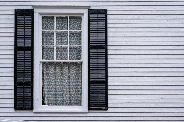 window with open shutters of an white colored wooden house