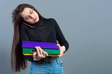 Akıllı telefonlu bir kadın elinde evraklı renkli bir klasör tutuyor, karanlık arka planda izole edilmiş.