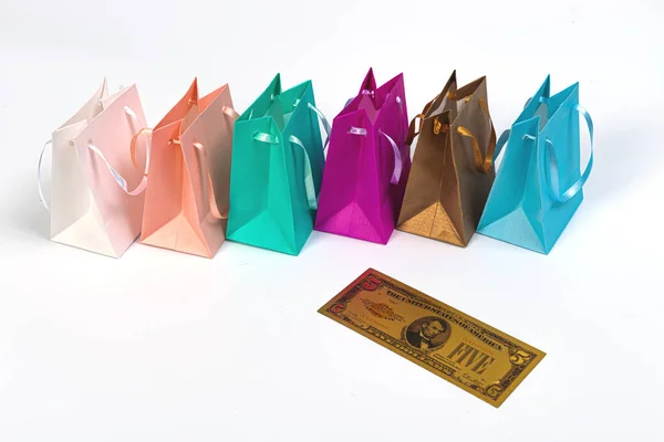 色彩艳丽的购物袋和白色背景隔离开的象征性的金元钞票 — 图库照片