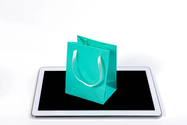 白色背景的现代平板电脑上的彩色小购物袋 网上购物概念 — 图库照片