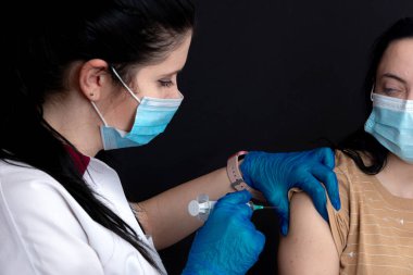 Hemşire korona virüsüne karşı aşı yapıyor. Korona virüsünün salgınını önlemek için.