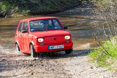 Madona, Letonya - 01 Mayıs 2021: Kırmızı eski araba Fiat 126 su engelini aştı