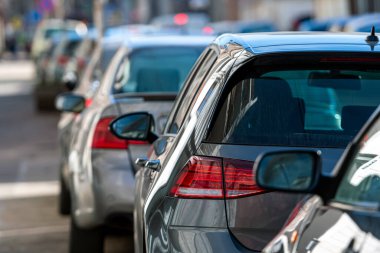 Kalabalık şehirde yol kenarına park edilmiş sıra sıra farklı arabalar, yakın çekim, seçici odak