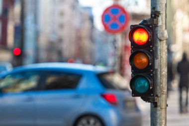 Şehir trafiğinin arka planına kırmızı ışık yakan küçük bir trafik semaforu.