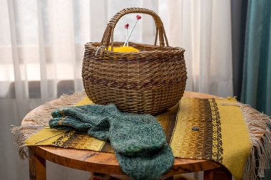 Eski model iç döşeme, örgü çoraplar ve hasır sepet. Yuvarlak ahşap bir masa üzerinde ahşap bir battaniye, yakın çekim.