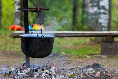 Ormandaki kamp ateşinde yemek pişirmek, yemek kampı konsepti kırsal kesimdeki evde şenlik ateşi yakmak.